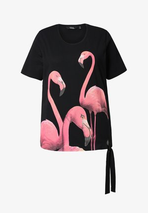 T-shirt noir avec un imprimé de trois flamants roses. Manches courtes, col rond et détail de lien sur le côté au niveau de l'ourlet.