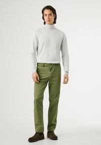 Gray turtleneck sweater, fitted; green trousers, tapered leg with belt loops and button closure; brown ankle boots with elastic sides.
