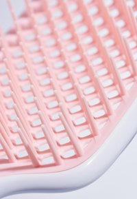 Plastborste med rosa rutmönster och vit bas. Flexibla borststrån arrangerade i rader, utformade för att reda ut håret.