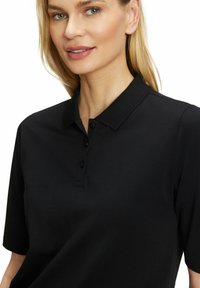 Zwarte poloshirt met een gestructureerde stof, korte mouwen en een placket met drie knopen. De geaccentueerde kraagdetail completeert het ontwerp.