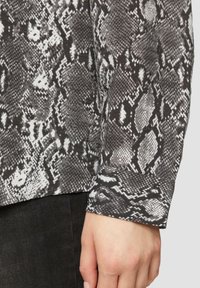 Langarmshirt in een zwart-wit slangenprint, met een zachte textuur en een aansluitend manchetontwerp.