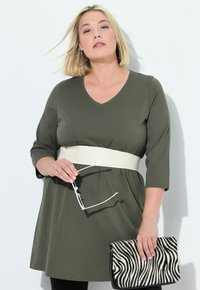 Olivgrön tunikaklänning med V-ringning, trekvartslånga ärmar och ett krämfärgat bälte. Matchad med en zebra-tryckt clutchväska och klara glasögon.