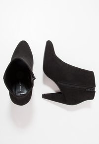 Mustat mokkanahkaiset nilkkasandaalit, joissa on teräväkärkinen malli, sivuvetoketju ja kapeat korot. Tasainen pinta ja minimalistinen muotoilu.