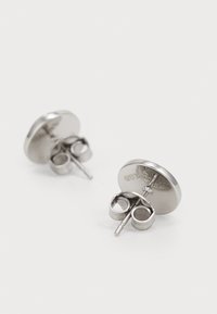 Silver stud earrings with a circular, flat design. Features a push-back closure. Smooth texture with a reflective surface.