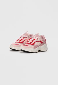 Baskets FILA rose et rouge avec des semelles blanches épaisses et des lacets blancs, inclinées vers la gauche sur un fond blanc uni.
