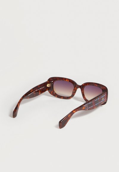 Lunettes de soleil rectangulaires en écaille de tortue marron avec verres dégradés et strass décoratifs sur les branches, sur fond blanc.