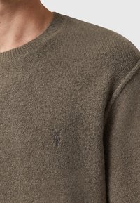 Olijfgroen gebreid trui met een ronde hals, voorzien van een subtiel geborduurd logo op de borst en een getextureerde afwerking.