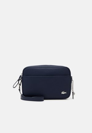 Bolso de mano rectangular azul marino con superficie texturizada, tirador de cremallera plateado y pequeño logo de cocodrilo en el bolsillo delantero.