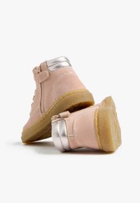 Rosa Wildleder-Stiefeletten mit silbernem Metallic-Akzent an der Ferse, ausgestattet mit seitlichen Reißverschlüssen und strukturierten Gummisohlen.