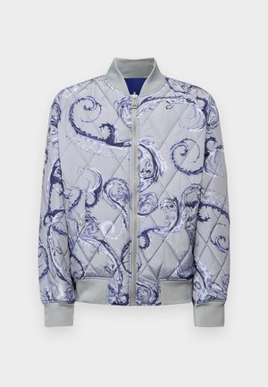 Quilted bomber jacket in light gray with blue floral swirl pattern. Features a front zipper, ribbed cuffs, and two side pockets.