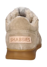 Beige suède sneaker met een fluffy voering, gumzool en een gestikte leren patch met het label "SHABBIES" op de hiel.