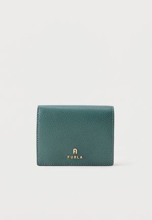 Portefeuille en cuir texturé vert avec logo doré Furla sur le devant, sur un fond uni gris clair.