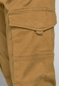Tan cargo pants with multiple pockets, featuring a sturdy cotton blend fabric, reinforced stitching, and a smooth texture.