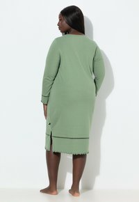 Vihreä, pitkähiha yöpaita, jossa on aaltoileva helma ja sivuhalkiot, valmistettu pehmeästä kankaasta, ja siinä on hienostunut somiste hihojen reunoilla.