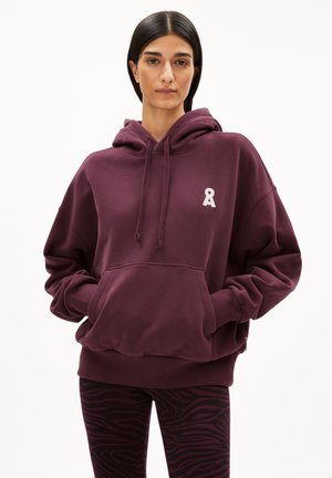 Bordeauxfarbener, übergroßer Hoodie mit einer vorderen Tasche und einem gestickten Bändern-logo. Kombiniert mit schwarzen und bordeauxfarbenen Leggings im Zebra-Design. Weicher Stoff.
