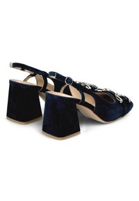 Sandalias de ante azul marino con tacón bloque y diseño de talón descubierto, que cuentan con un acento de cadena plateada en la parte delantera.