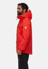 Rote wasserfeste Jacke mit Kapuze, Reißverschluss-Taschen und elastischen Bündchen. Verfügt über ein Logo auf dem Ärmel und ein schlanke, funktionales Design.