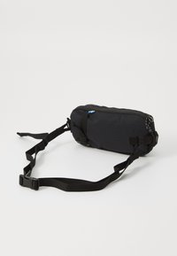 Borsa in vita nera, imbottita, con corde regolabili. Presenta una chiusura con zip e un piccolo accento a forma di bandiera. Design compatto ed ergonomico.