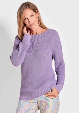 Lavendelfarbener, gestrickter Pullover mit weitem Ausschnitt, strukturiertem Muster und gerippten Bündchen, kombiniert mit gemusterten Pastellhosen.