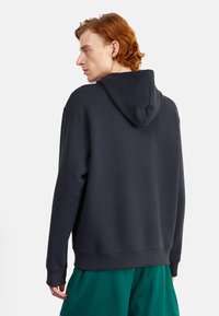 Sweatshirt à capuche gris foncé avec une coupe décontractée, des poignets et un ourlet côtelés. Texture lisse, avec une poche kangourou à l'avant.