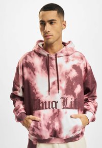 Felpa con cappuccio caratterizzata da un motivo tie-dye rosa e bianco, tasca a marsupio e audace grafiche "Thug Life" nera sul davanti.