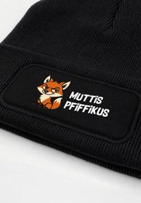 Black knitted beanie featuring a large, black fabric patch with a cartoon fox graphic and the text “MUTTIS PFIFFIKUS” in white.