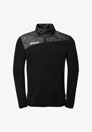 Schwarze Sportjacke mit durchgehendem Reißverschluss, grauem Yoke mit geometrischem Muster und weißem "Kempa"-Logo auf der oberen linken Brust.