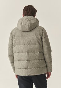 Hall puffer-jope kapuutsiga, mis on valmistatud tekstureeritud kangast ja horisontaalse pitsilise disainiga. Seljal on õmbluse detail ja pehme viimistlus.