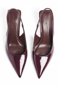 Burgundijas lakota ādas siksnīšu papēži ar izteiktām purngalām un atvērtiem sāniem, piedāvājot gludu iekšējo oderējumu un minimālistisku dizainu.