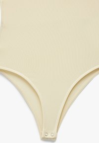 Bodysuit w kolorze kremowym, wykonany z gładkiego, teksturowanego materiału, o minimalistycznym designie i zapięciu na napy na dole.