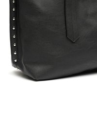 Sac fourre-tout en cuir noir avec une surface texturée, mettant en avant des clous argentés sur un côté et une sangle plate pour le porter.