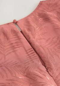 Rosa plagg med broderade bladmönster, rundad halsringning och bakre dragkedjestängning med en tygknapp som accent.