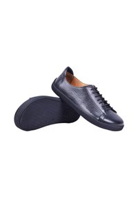 Paire de chaussures décontractées en cuir noir à lacets avec côtés perforés et semelles en caoutchouc, une montrant la vue du dessus et l’autre la semelle.