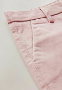 Lichtroze katoenen broek met een vlakke tailleband, voorkwasten en zichtbare stikdetails. Glad oppervlak en getailleerde pasvorm.