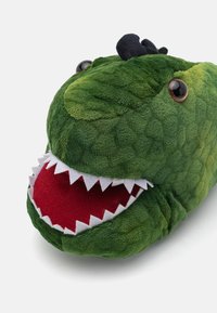 Grønn dinosaur kosedyr med myk tekstur, som har store øyne, en bred rød munn med hvite tenner, og svarte aksenter på toppen.