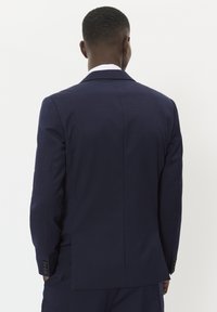 Mornarsko plava jakna odijela s jednim prorezom na leđima, dugim rukavima i detaljima dugmadi na manžetama. Glatka tekstura, prilagođen dizajn.