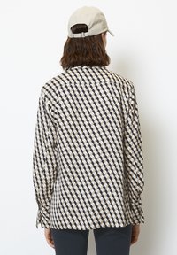 Camicia con motivo geometrico in blu navy, crema e oro. Realizzata in tessuto leggero, con maniche lunghe e vestibilità ampia.