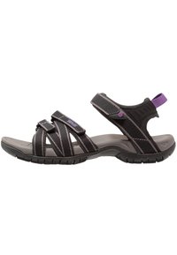Sort sandal med krydsremme, struktureret stof og justerbart Velcro. Holdbar gummisål med en lilla detalje på hælremen.