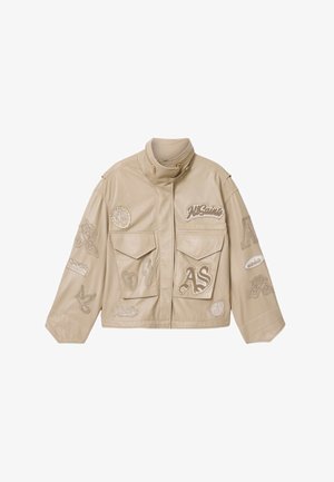 Beżowa skórzana kurtka ze stojącym kołnierzem, przednimi kieszeniami oraz haftowanymi naszywkami, w tym "AS", różą, sercem, błyskawicą i wzorami ptaków.