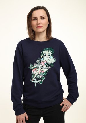 Mørkeblå crewneck sweatshirt med grafisk tryk af en tegneseriemester, omkranset af blade og et banner med tekst. Blødt, tekstureret stof.