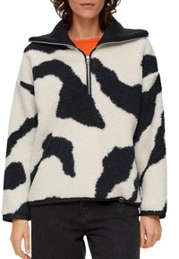 Polarowy sweter z wysokim kołnierzem, z czarno-kremowym abstrakcyjnym wzorem, zamek błyskawiczny oraz elastyczny dół. Teksturowana powierzchnia.