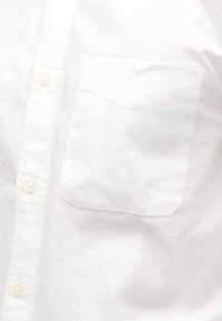 Camicia bianca con bottoni e taschino applicato, realizzata in tessuto leggero con una texture liscia e un leggero effetto lucido.
