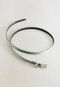 Tynd grøn metalbælte med en glat overflade. Har en firkantet sølvspænde og flere justeringshuller til tilpasning.