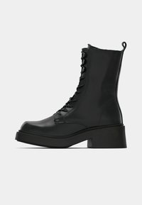 Μαύρες δερμάτινες μπότες αστραγάλου με χοντρό, στιβαρό τακούνι, δέσιμο μπροστά και δακτύλιο για να τις τραβάτε από πίσω. Λείο υλικό, μινιμαλιστικός σχεδιασμός.