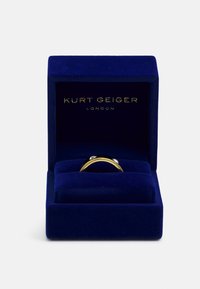 Gouden ring met twee heldere edelstenen, gepresenteerd in een blauwe fluwelen doos met "Kurt Geiger London" in goud gebosseleerd op de binnenkant.