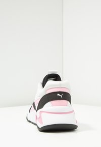 White, pink, and black Puma sneaker viewed from the back, showing the heel and logo on a white surface with a plain background.