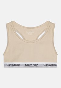 Beige bomulls-bh med racerback-design og et svart-hvitt Calvin Klein-logo bånd nederst. Størrelse indikert: 8/10 år.