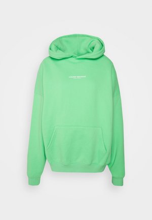 Green hooded sweatshirt made of soft fabric featuring a front pocket and embroidered text "WORST BEHAVIOR" in white on the chest.