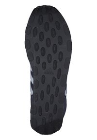 Czarna, sportowa podeszwa buta z teksturowanej gumy, posiadająca owalne wycięcia i wyraźne logo. Zawiera trzy białe paski po bokach.