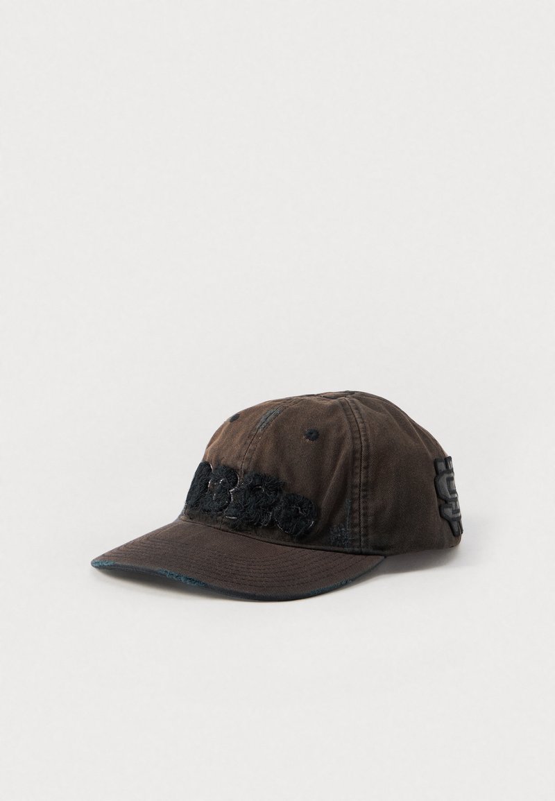 Gorra de tela marrón con visera curva, con acentos texturizados en negro y detalles bordados en la parte frontal. Aspecto desgastado y un ajuste relajado.